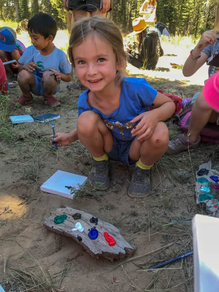 girl painting outside on a small canvas