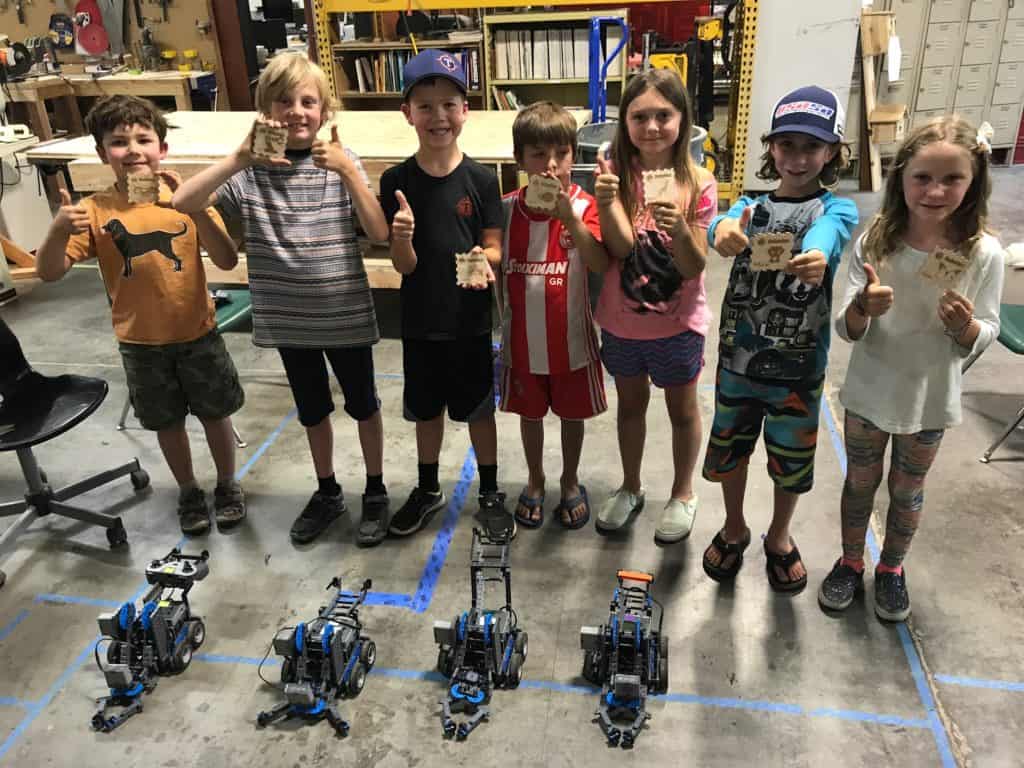 kids standing behind their robots