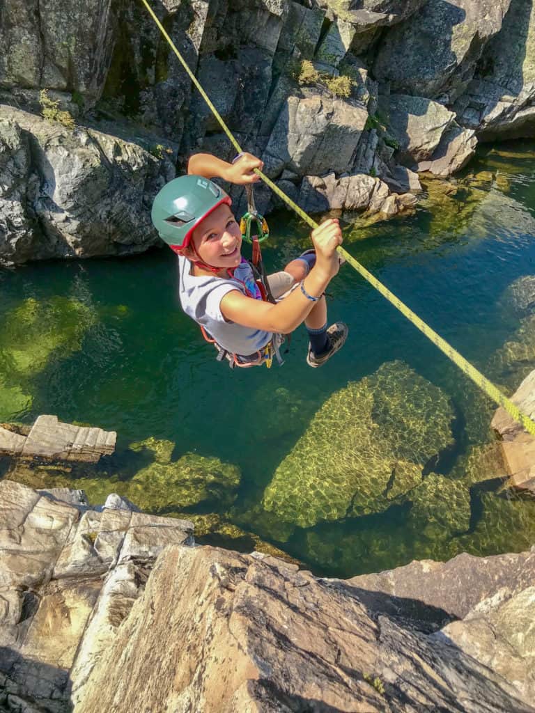 boy in a rope harness crossing a line over a river