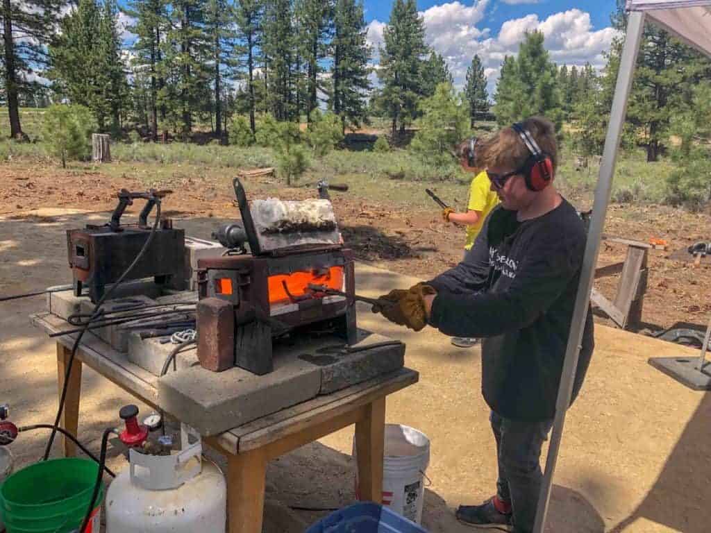 student working a forge outdoors