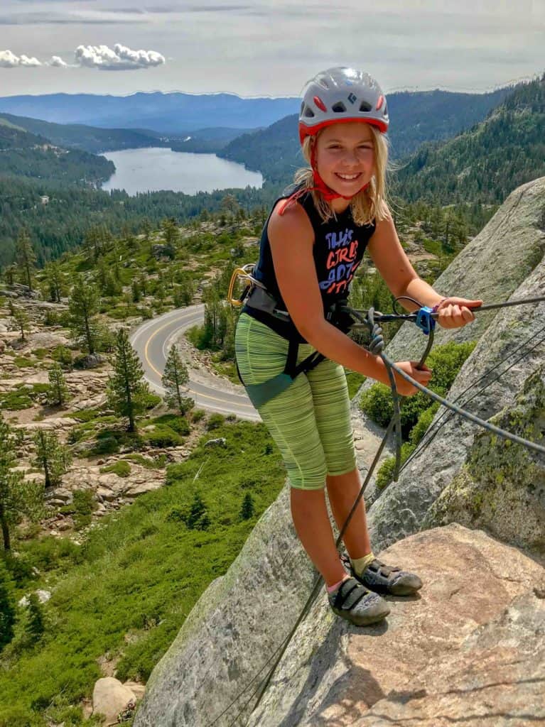 girl in a rope harness decending a cliff