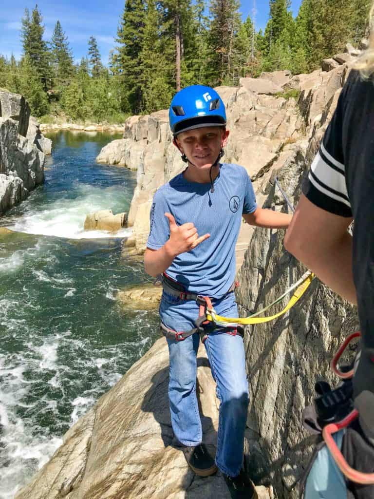 student rock climber walking beside a river