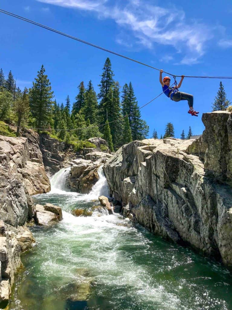 boy in a rope harness crossing a line over a river