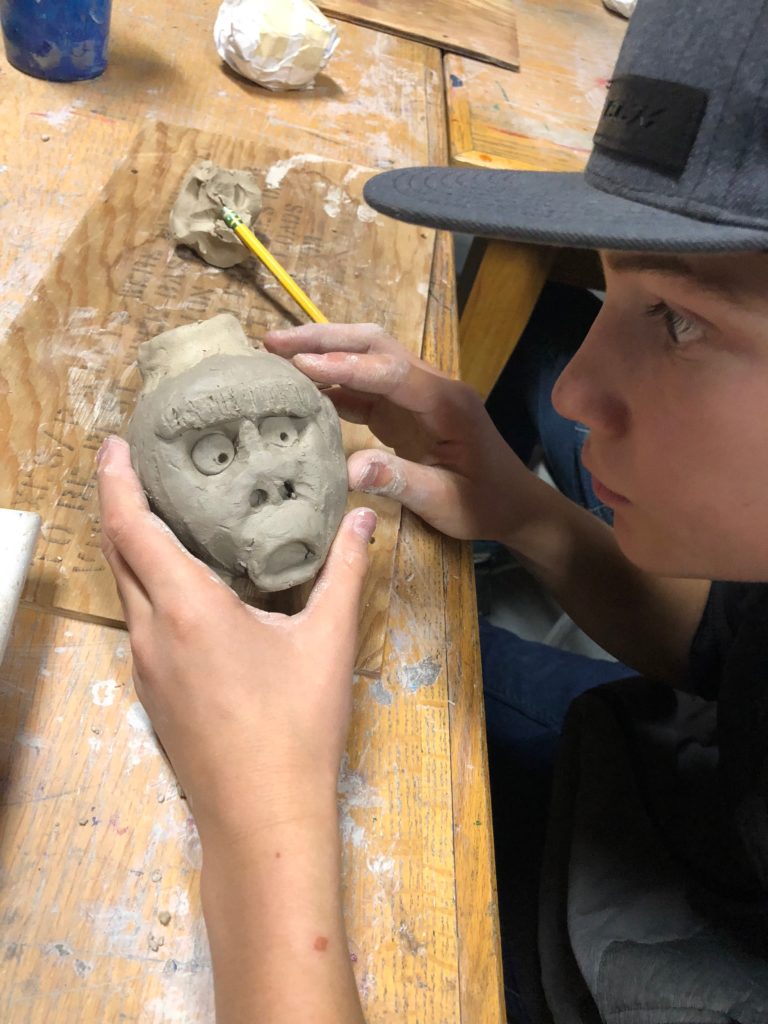art student holing a sculpted clay face
