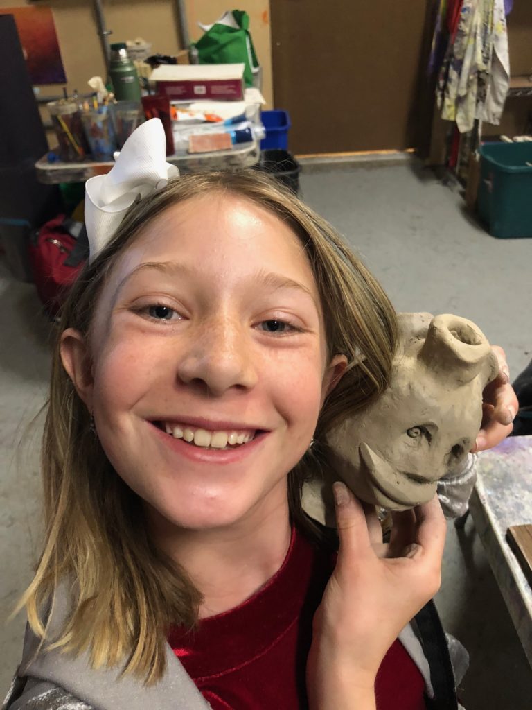 art student holding her unfired clay sculpture